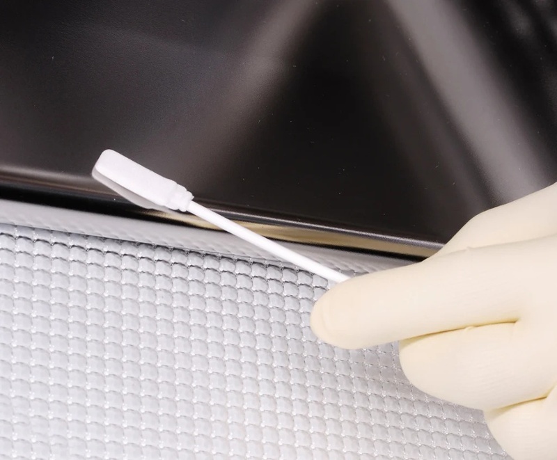 close up of white swab cleaning off black counter top