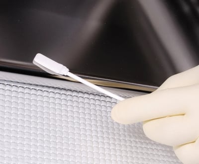 close up of white swab cleaning off black counter top