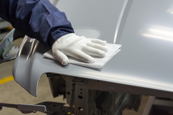 white glove wiping down hood of gray car part