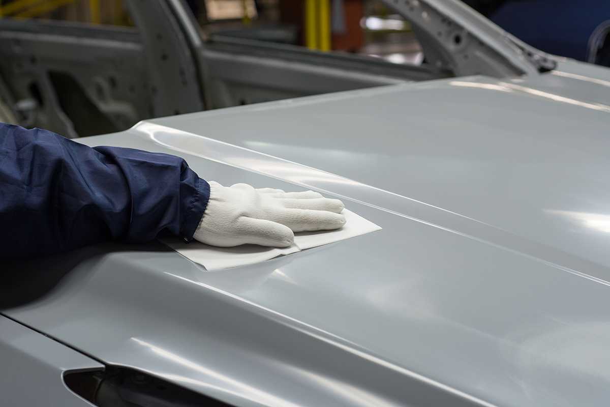 white glove wiping down hood of gray car