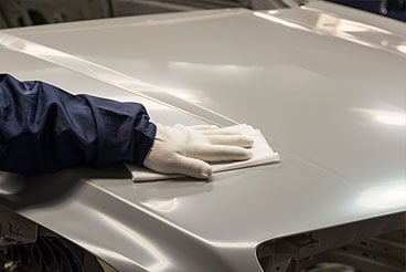 close up of glove wiping down hood of car